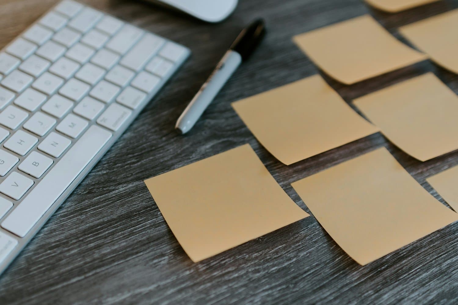 A desk with a keyboard, marker, and sticky notes used as the background for the agile consulting and training hero section.