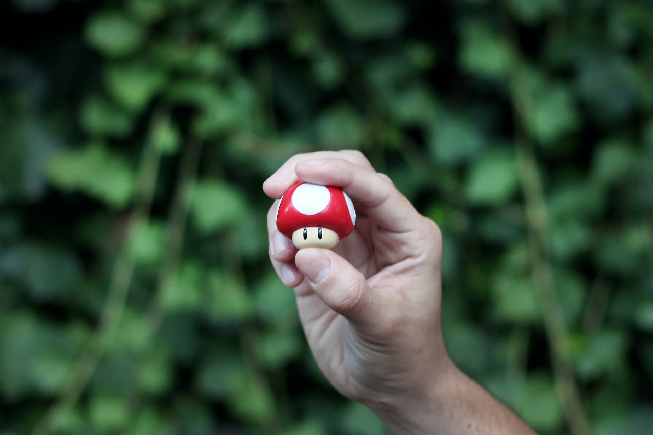 A hand holding a red and white game piece in front of a soft green background.
